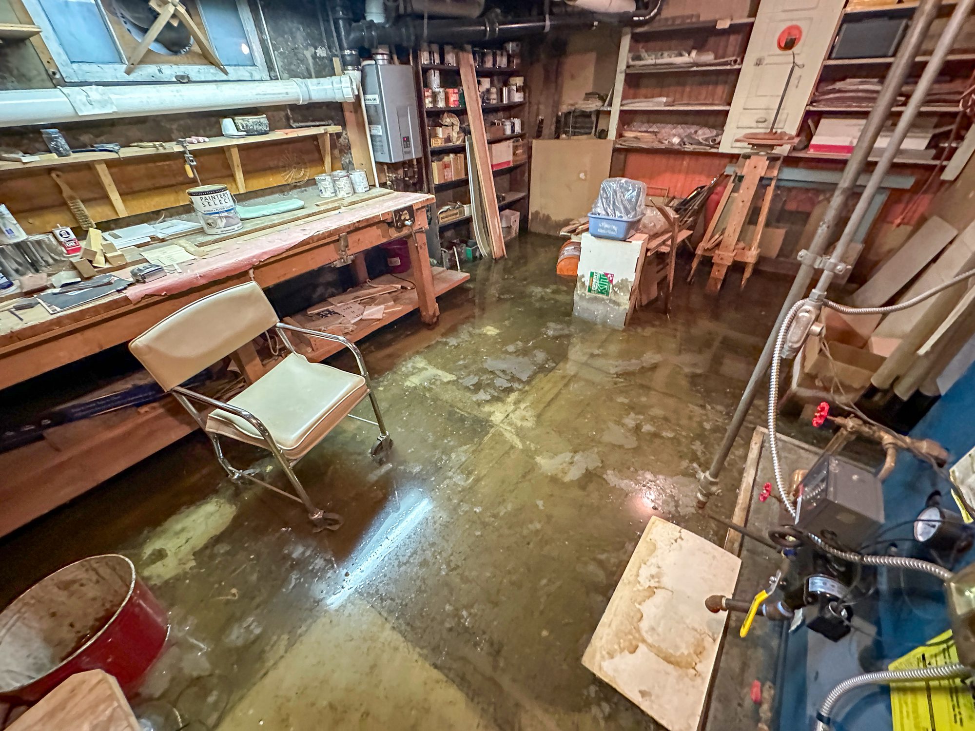 Flooded basement workshop with standing water.