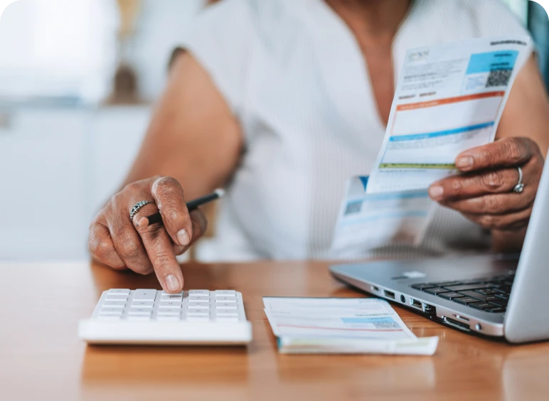 Person calculating bills with laptop and calculator.