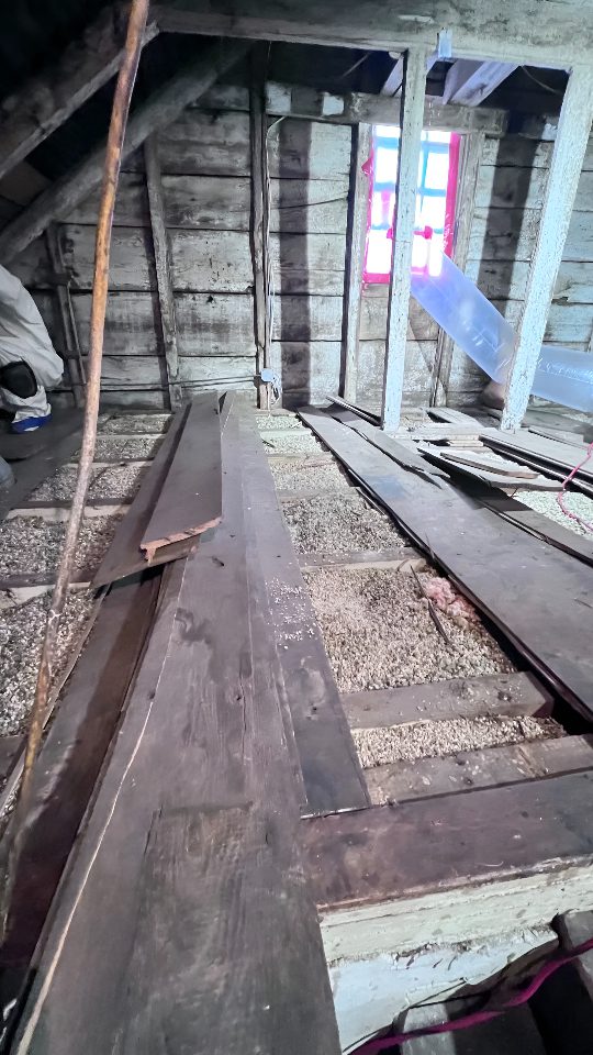 Old wooden attic with exposed beams and insulation